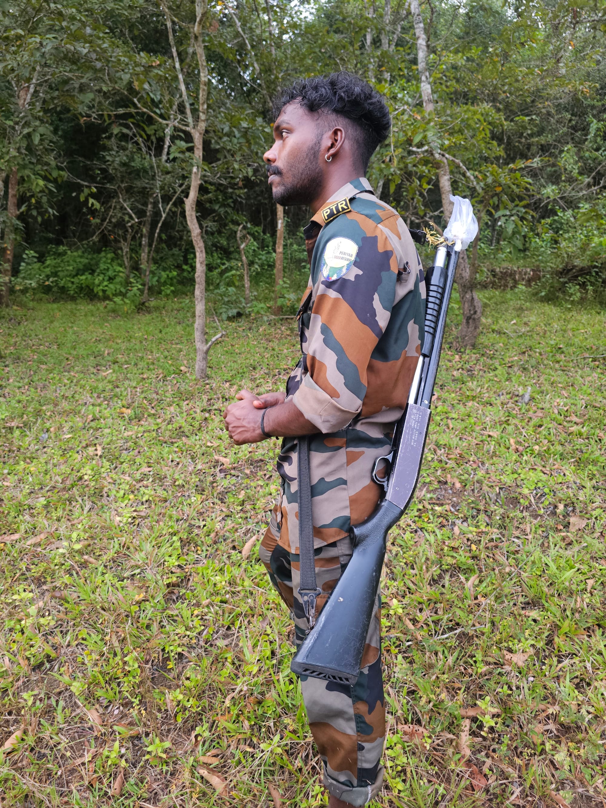 A forest guard in camouflage with a shotgun slung over his shoulder