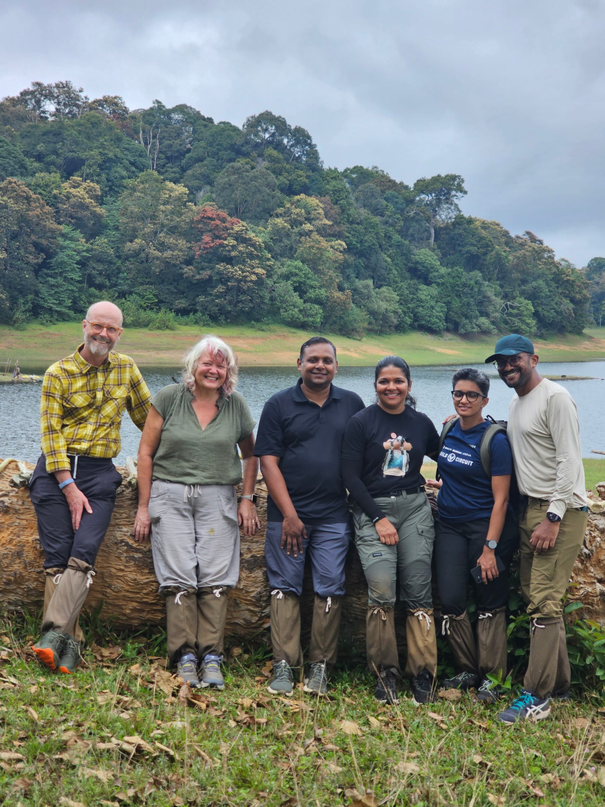 The six trekkers in leech socks against a fallen log by the lake
